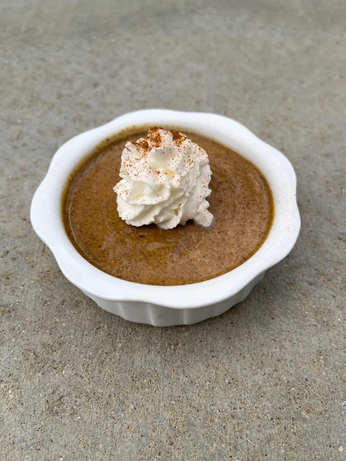 Pumpkin pie chia pudding cup topped with dollop of whipped cream and sprinkled of ground cinnamon.