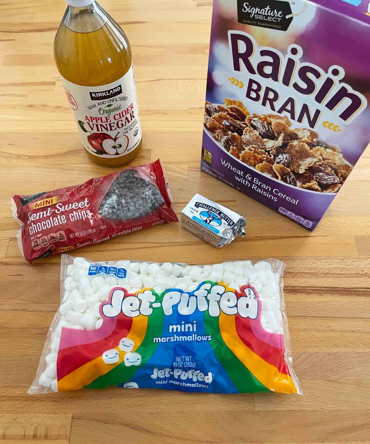 Ingredients for making cereal bars, including Raisin Bran cereal, mini marshmallows, mini chocolate chips, butter and apple cider vinegar.