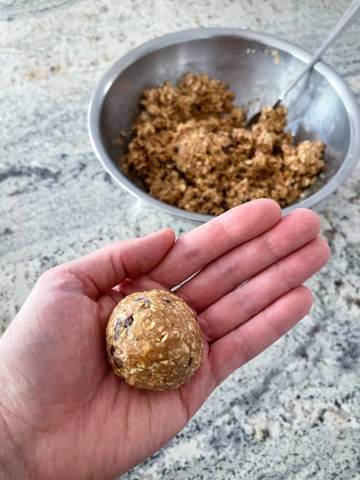 Rolling Kodiak no-bake protein bite mix in palm with mixing bowl in background.