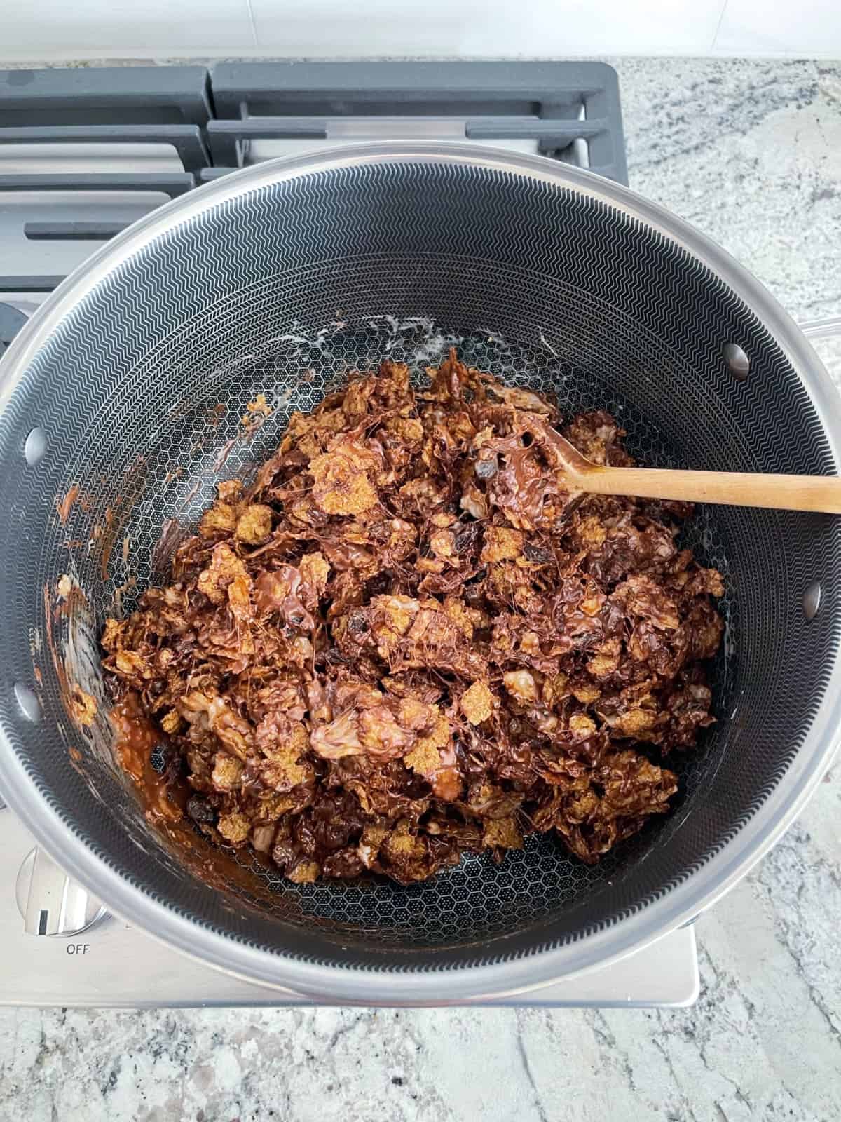 Stirring to coat Raisin Bran with melted marshmallow and chocolate mixture in saucepan.