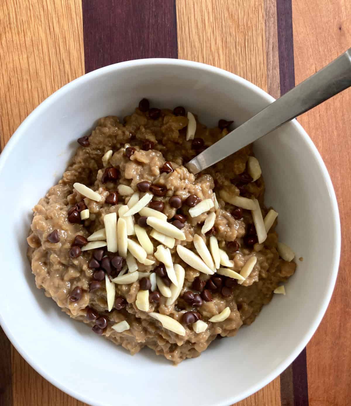 Bowl of oatmeal topped with mini chocolate chips and slivered almonds.