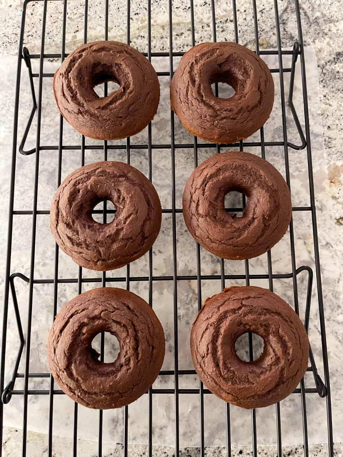 Mint chocolate donuts on wire cooling rack.