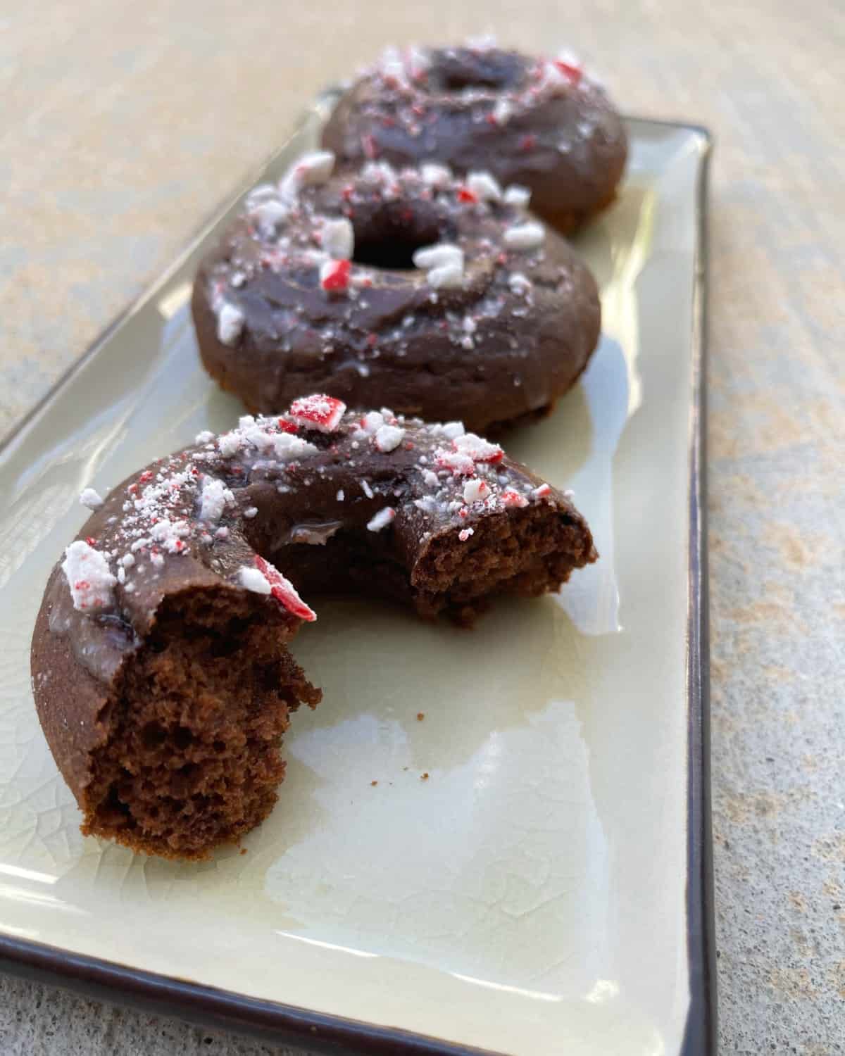 Two-and-a-half mint chocolate glazed donuts on rectangular platter.