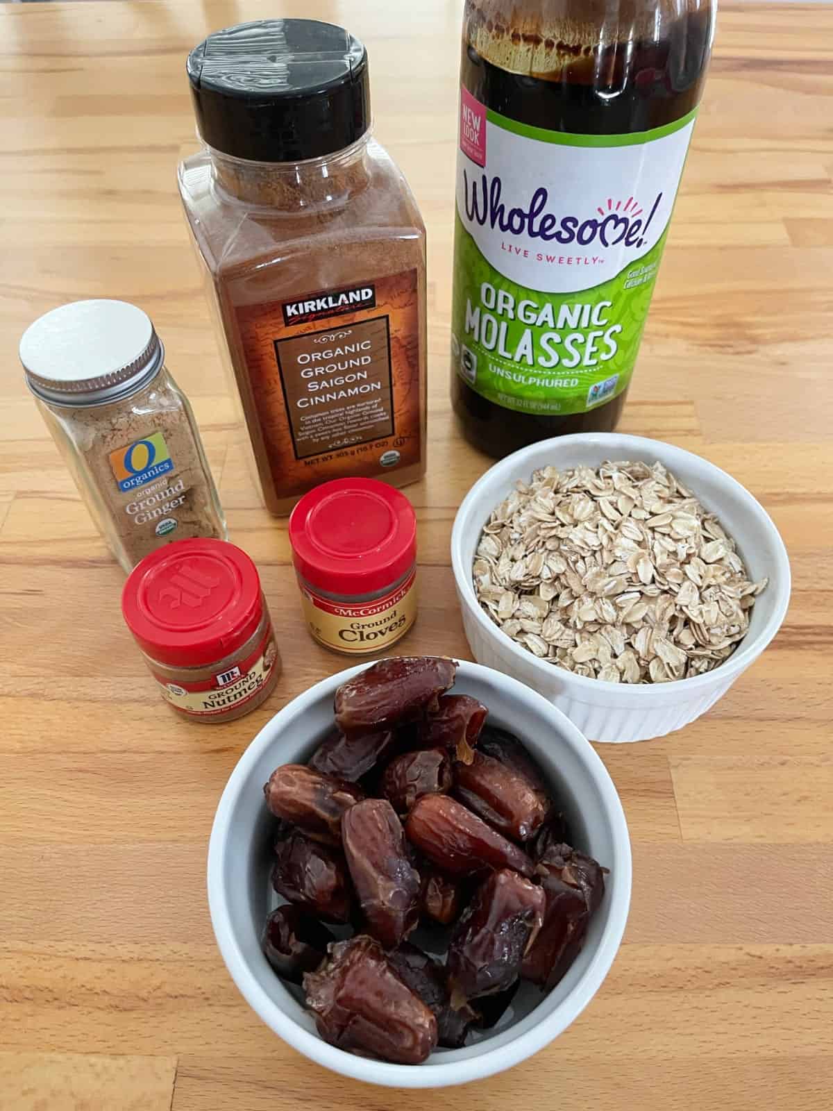 Ingredients for making gingerbread truffles including molasses, oats, dates, cinnamon, ginger, cloves and nutmeg.