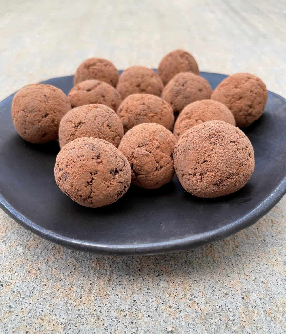Rum balls on brown pottery serving plate.