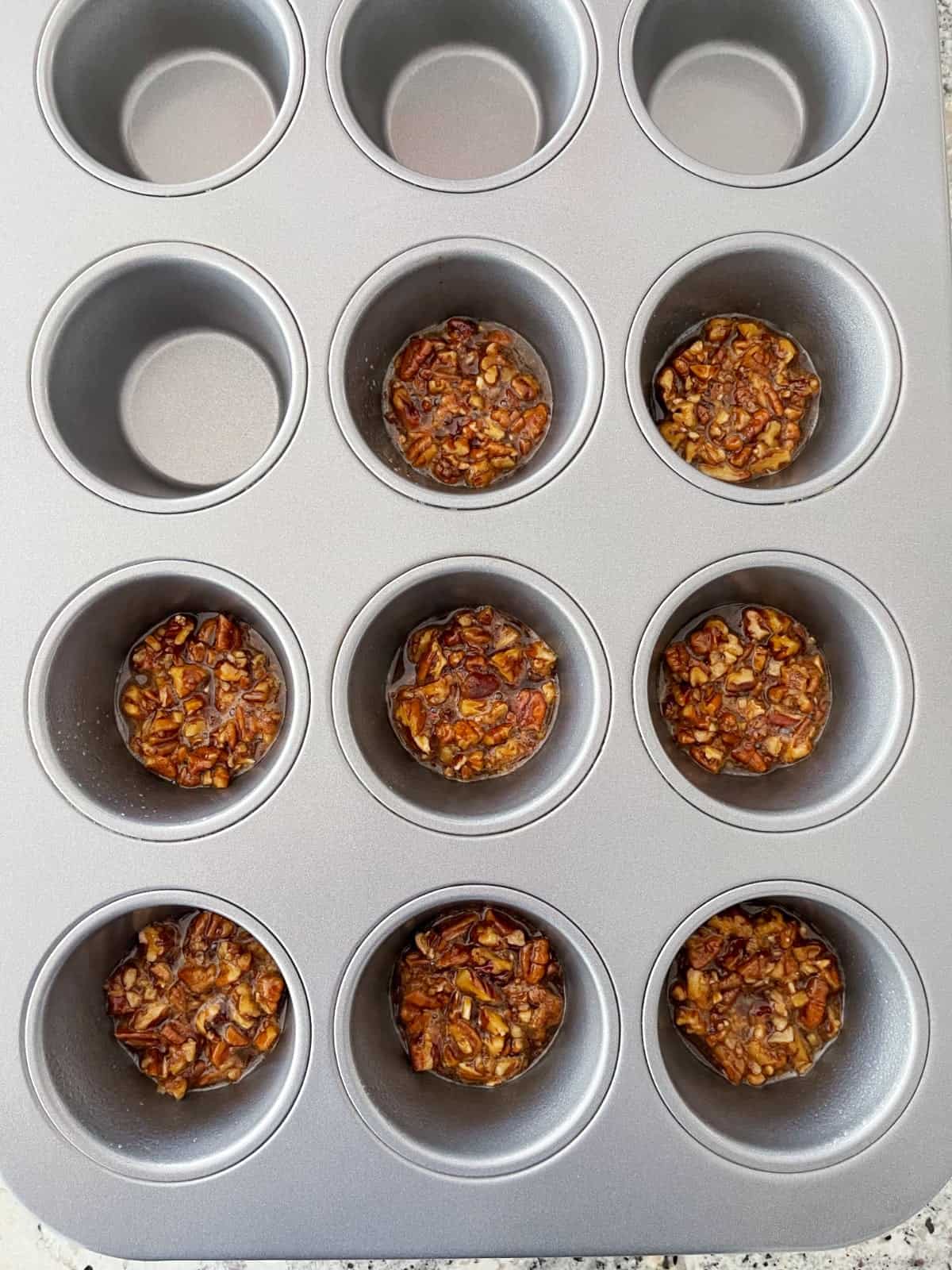 Pecan praline cookie batter in 8 cups of standard 12-cup muffin tin.