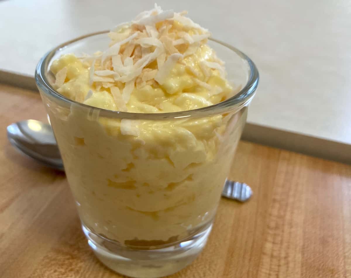 Glass with 3-ingredient pineapple fluff with spoon behind.