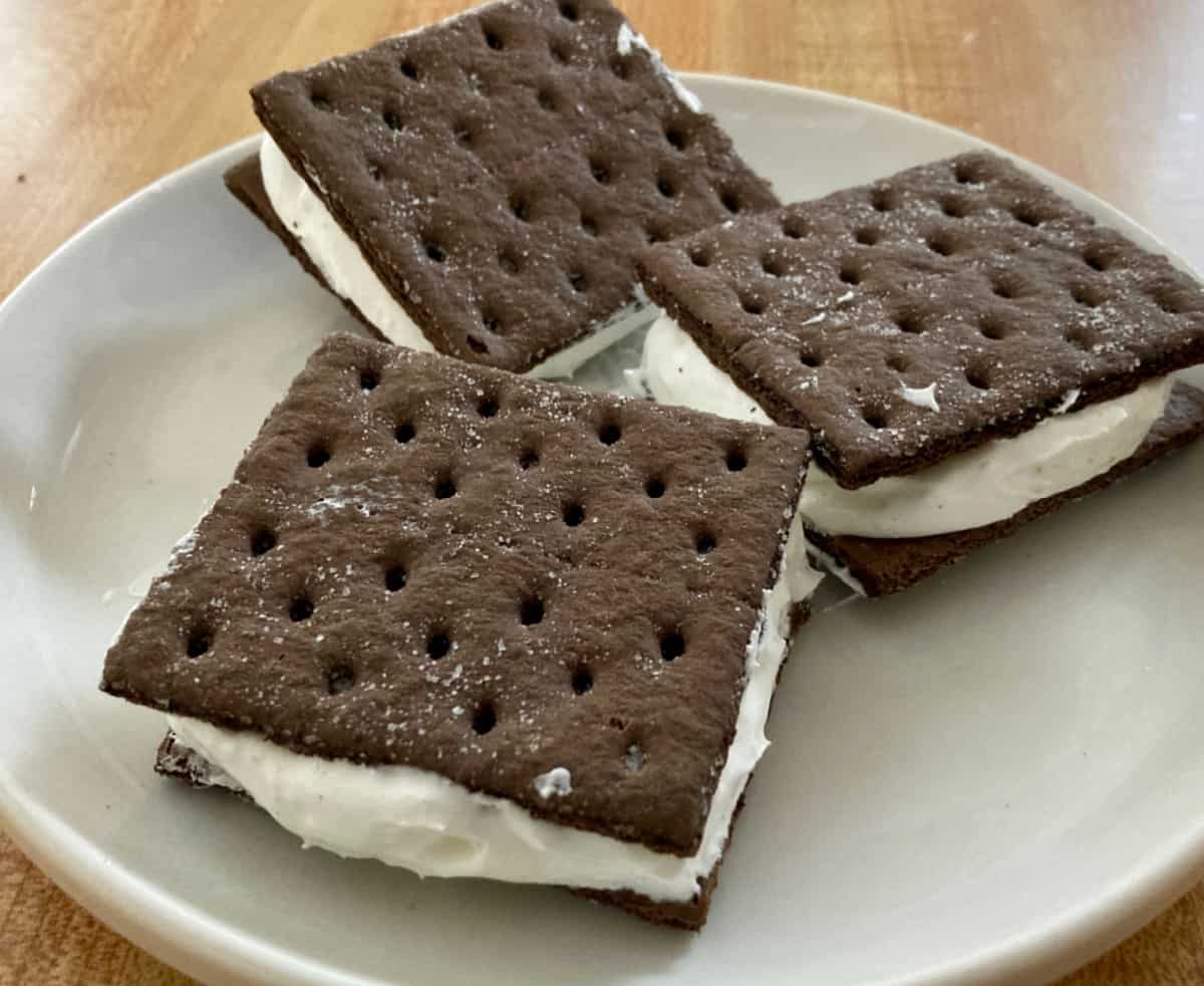 Frozen chocolate graham cracker cool whip sandwiches on a small plate.
