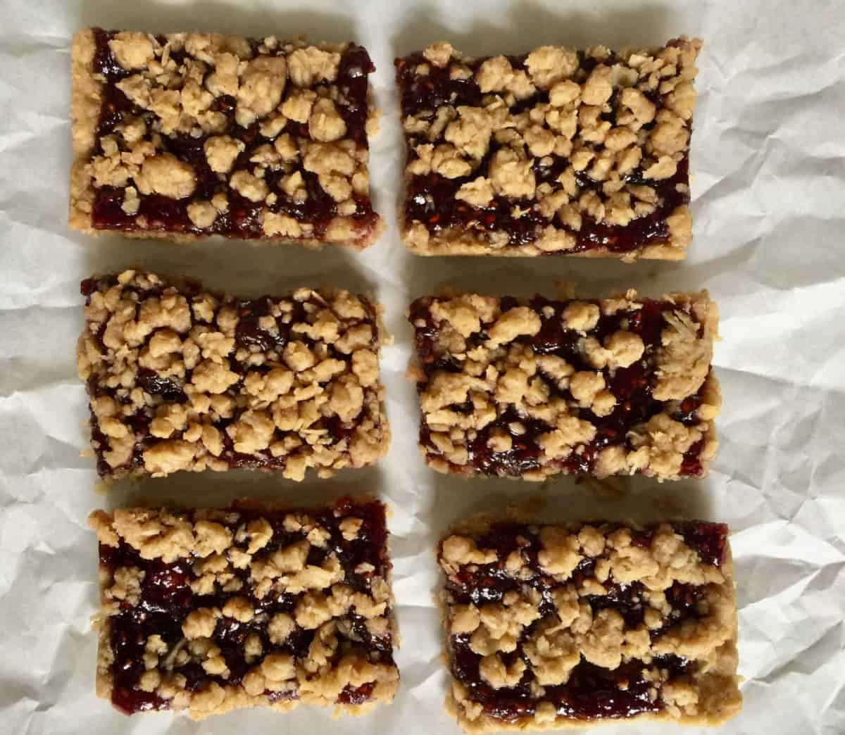 6 raspberry oat bars on parchment paper from above.
