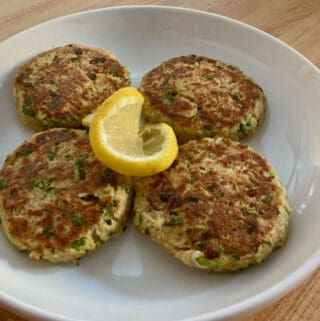 4 tuna patties on white plated with lemon slice in the center