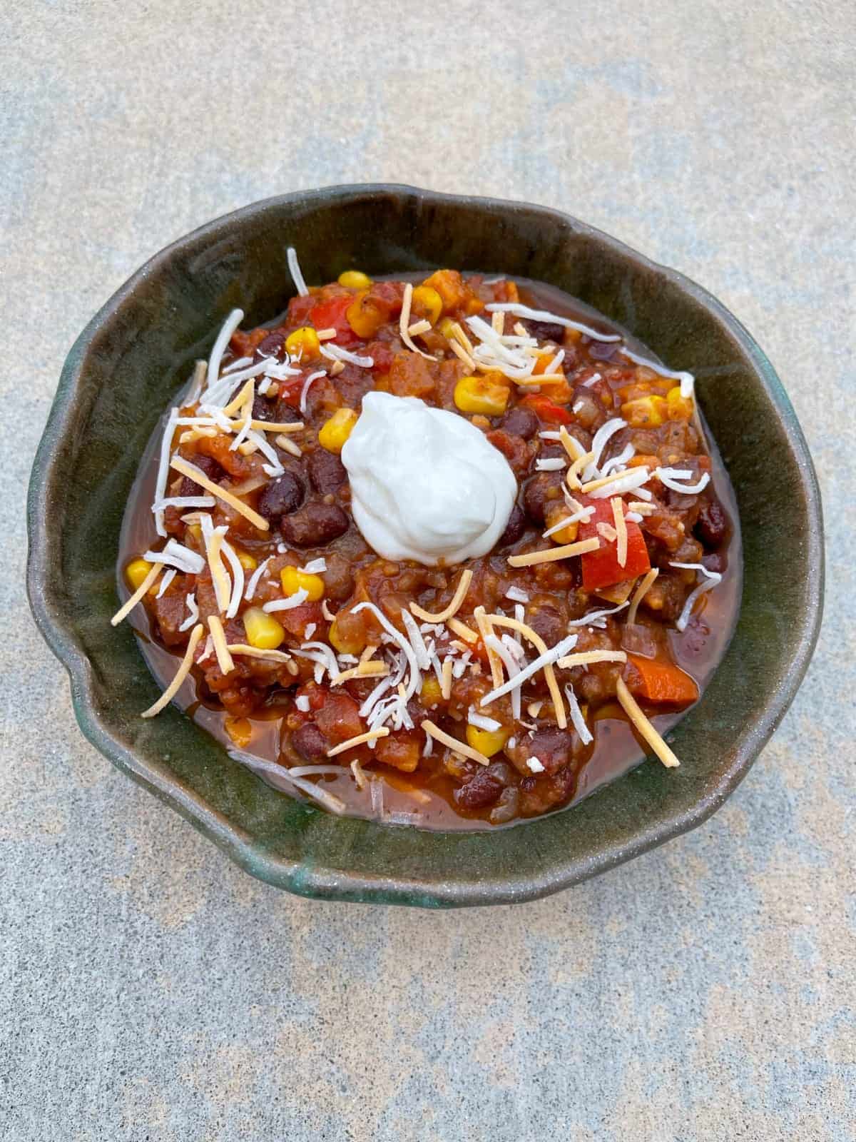 Vegetarian chili with black beans and sweet potatoes topped with shredded cheese and lite sour cream.
