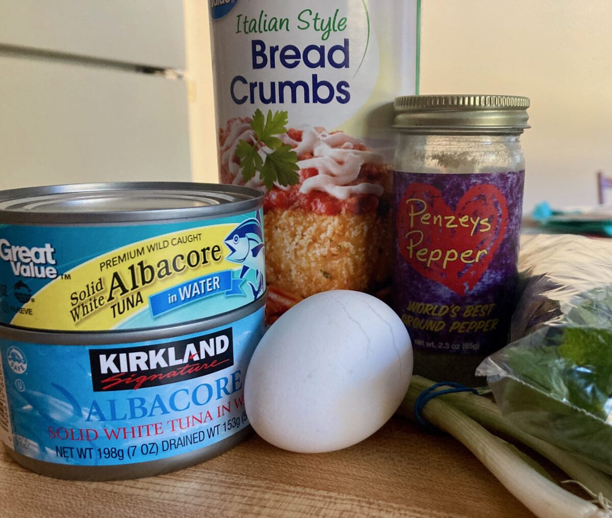 Ingredients for making tuna patties including canned tuna, bread crumbs, egg and spices.