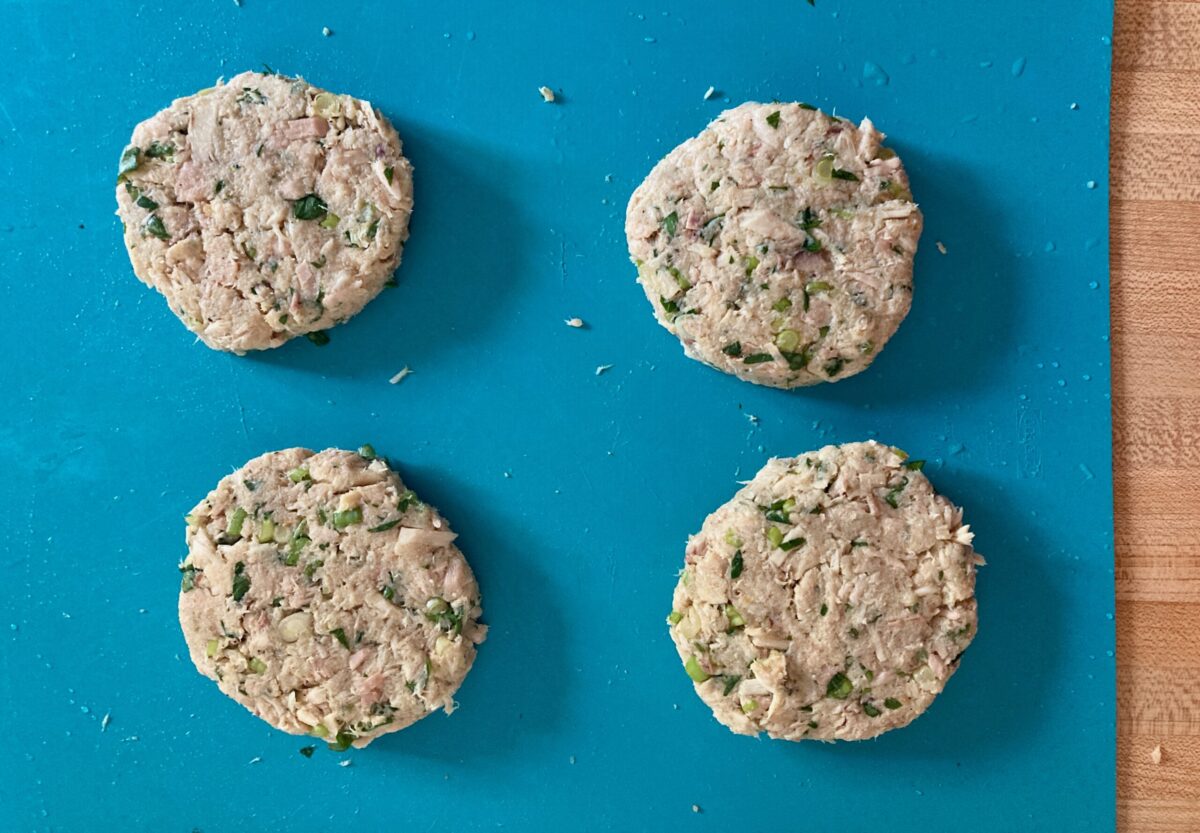 Four uncooked tuna patties on blue mat.