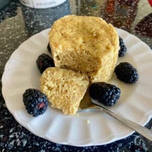 microwave flax muffin on white saucer surrounded by blackberries