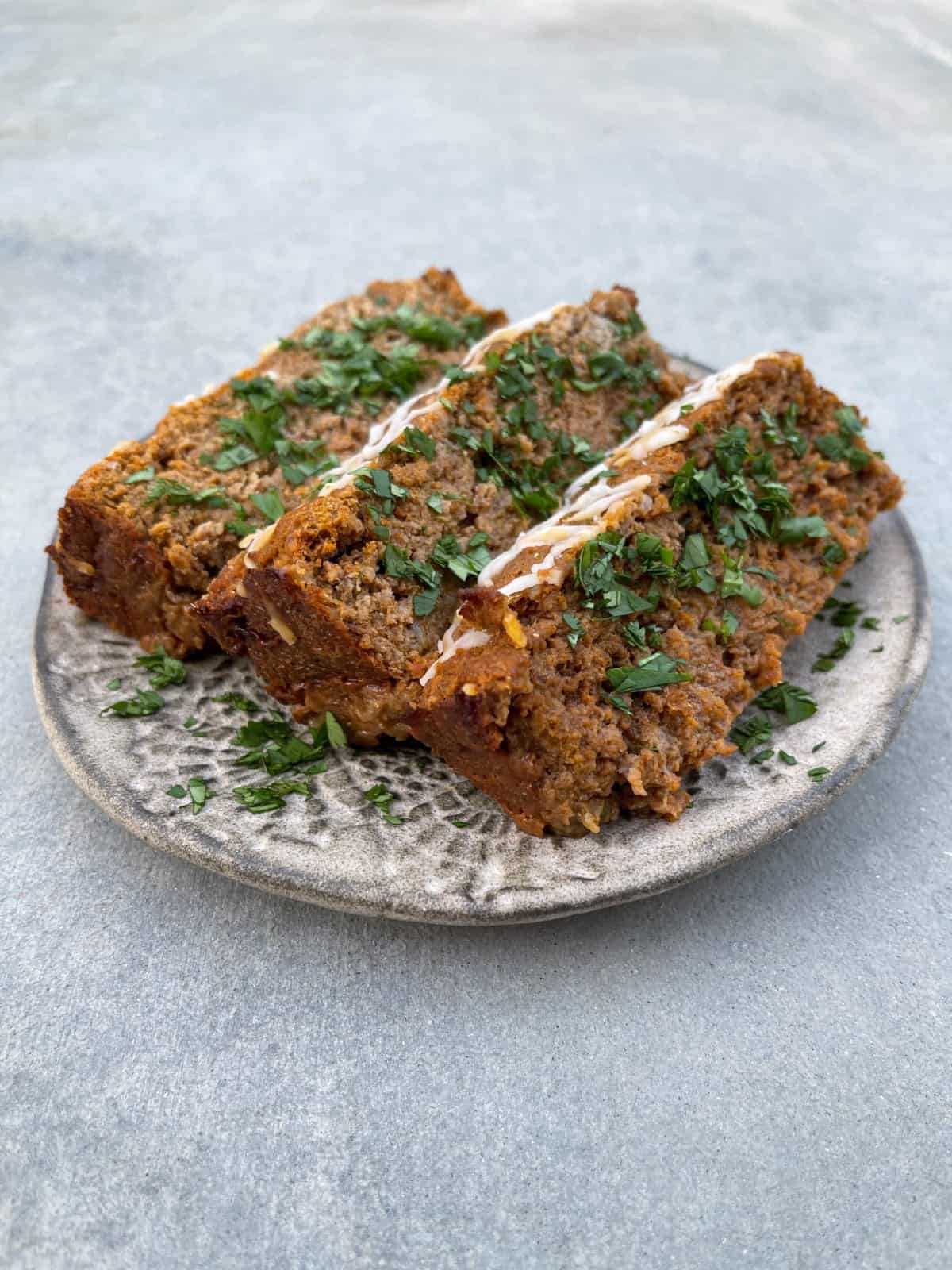 Textured Pottery Plate with 3 slices of meatloaf garnished with parsley.