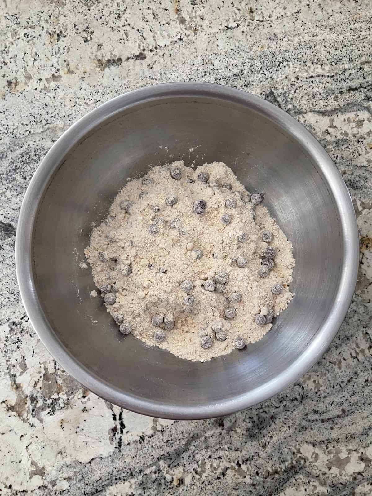 Tossing blueberries in mixture of baking mix, oats, sweetener and baking soda.