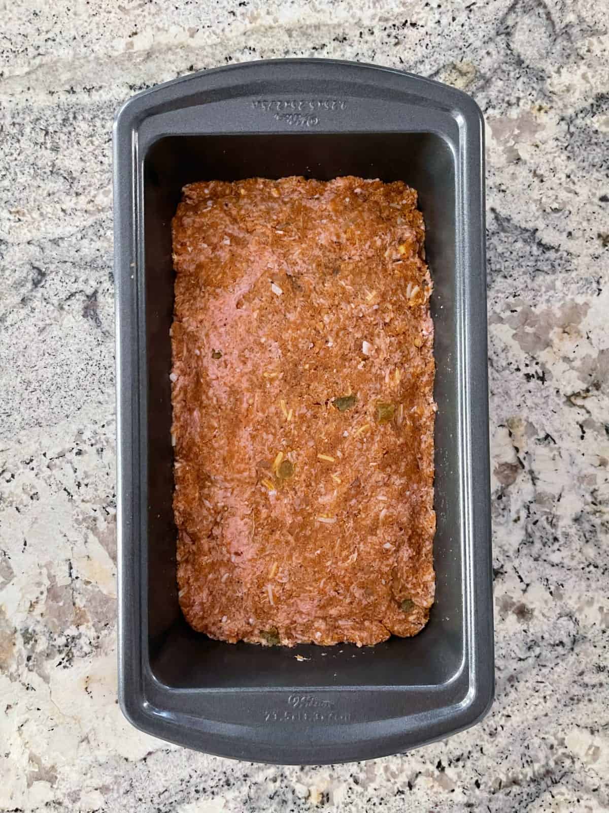 Uncooked salsa meatloaf in loaf pan on granite.
