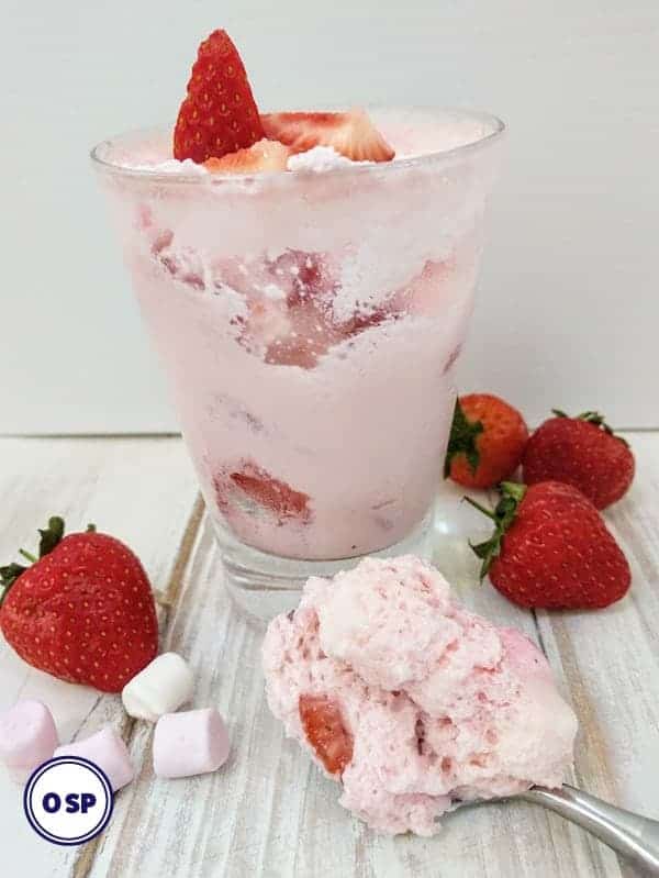 Marshmallow fluff with fresh strawberries in dessert glass with spoon.