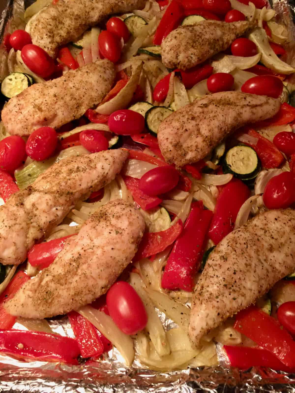 Sheet Pan dinner with chicken tenders, tomatoes, peppers, onions and zucchini.