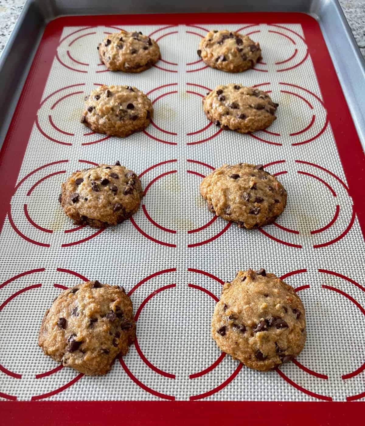 Fresh baked tablespoon chocolate chip cookies on baking sheet.