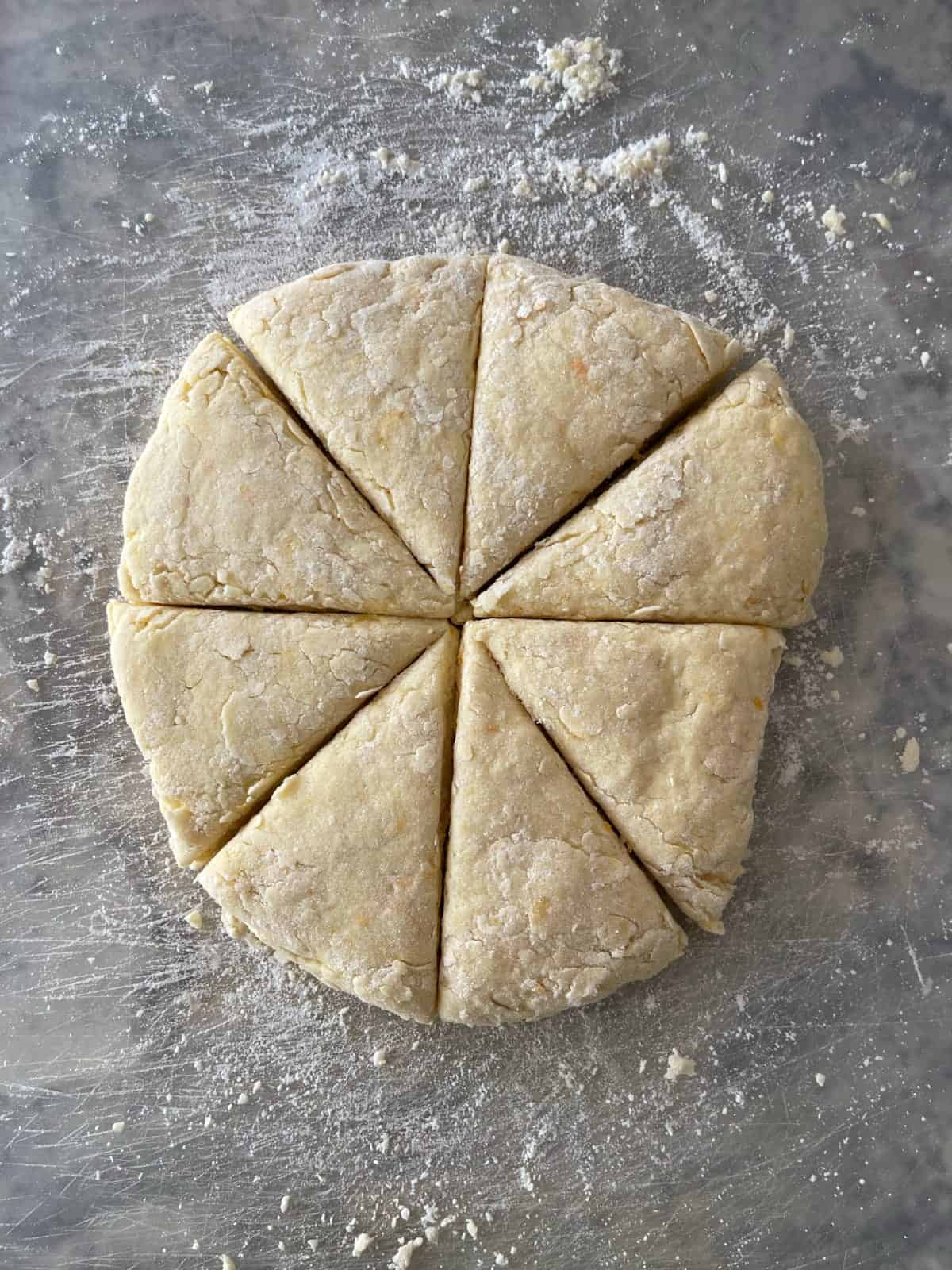 Orange scone dough cut into 8 wedges.