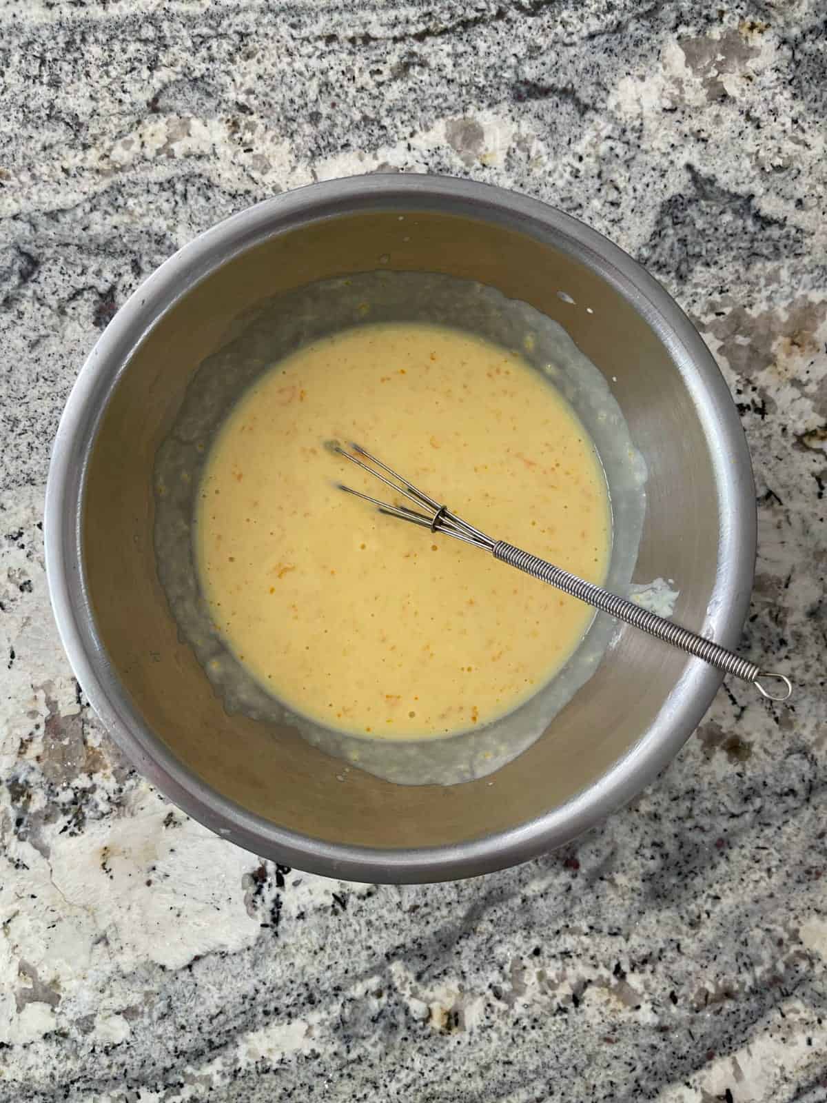 Whisking orange juice, orange zest, Greek yogurt and egg in mixing bowl.