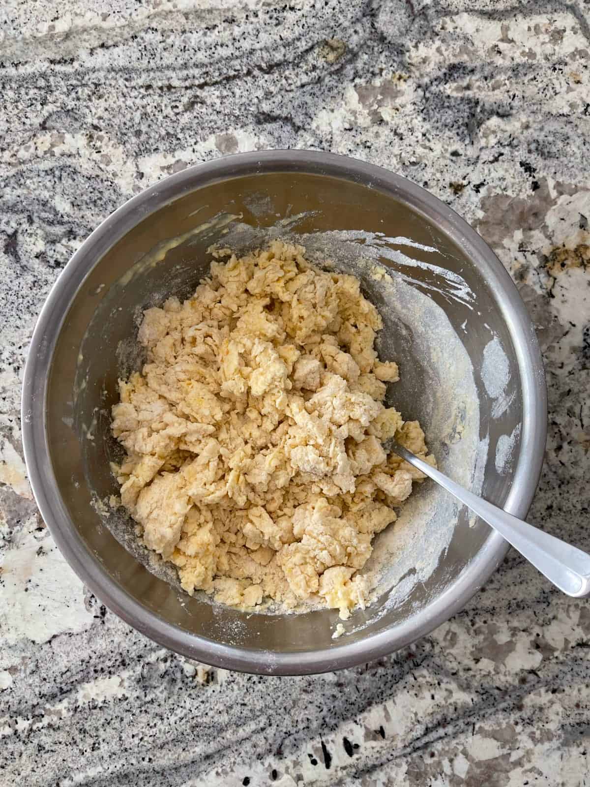 Mixing orange scone dough in mixing bowl with fork.