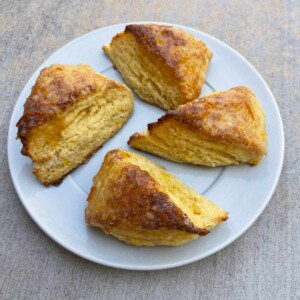 4 fresh orange scones on white plate from above