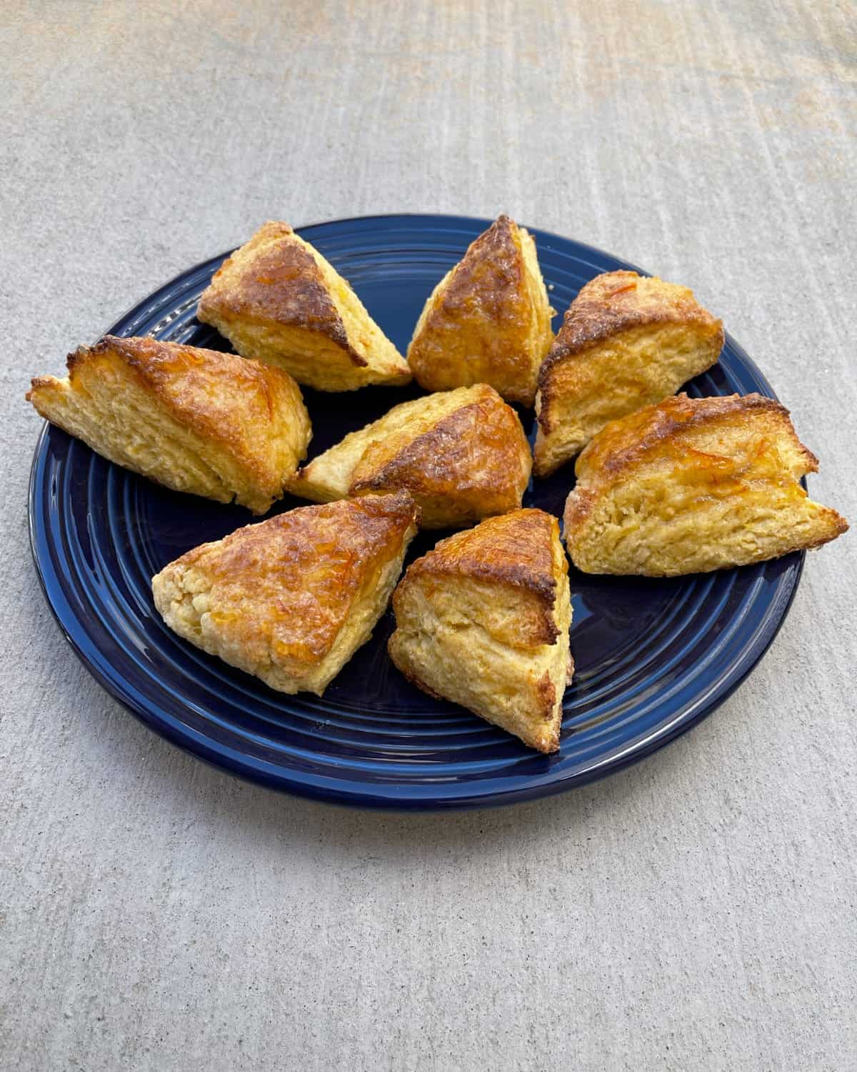 Fresh baked orange scones on blue platter.