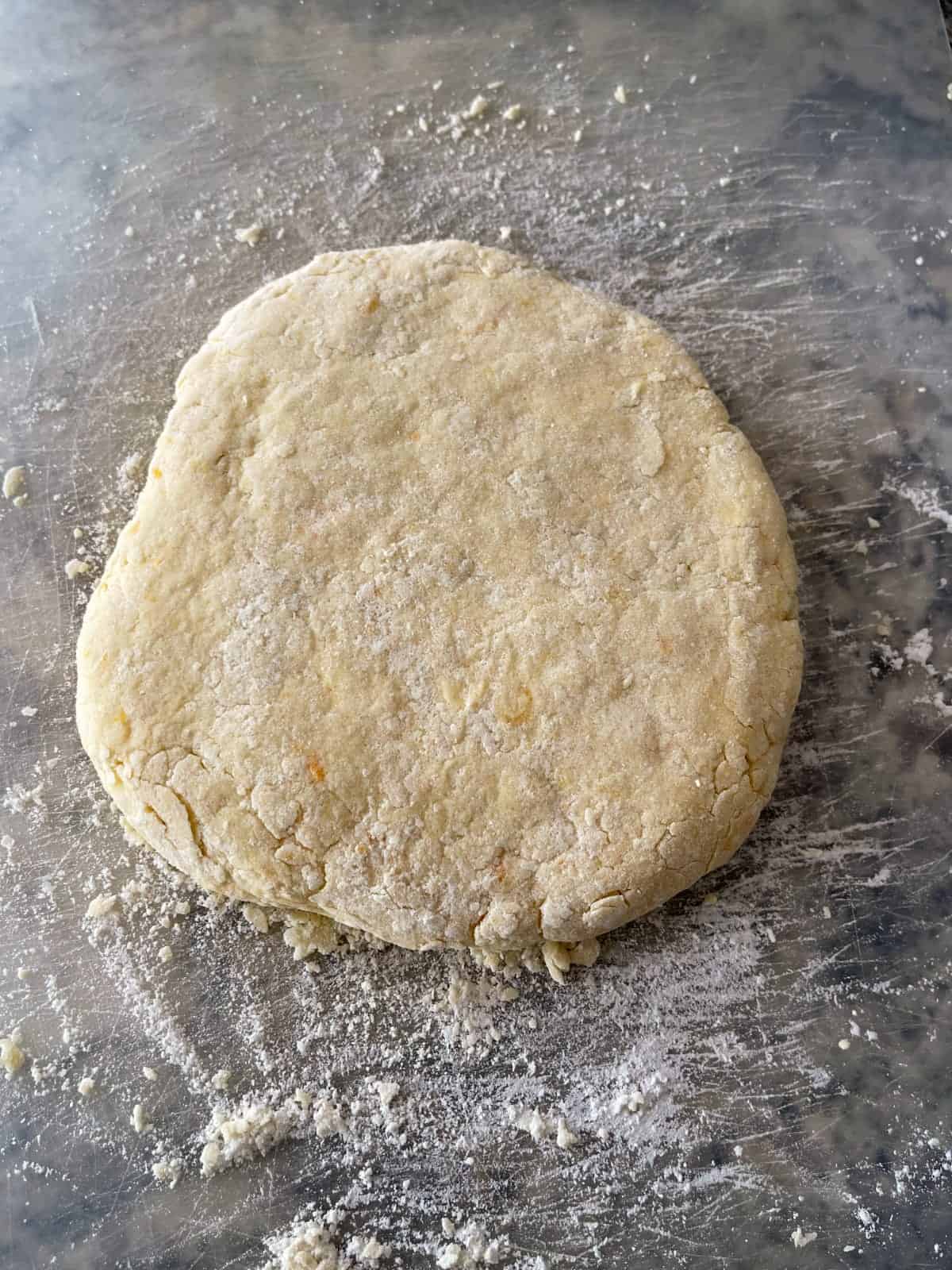 Kneaded orange scone dough on floured surface.