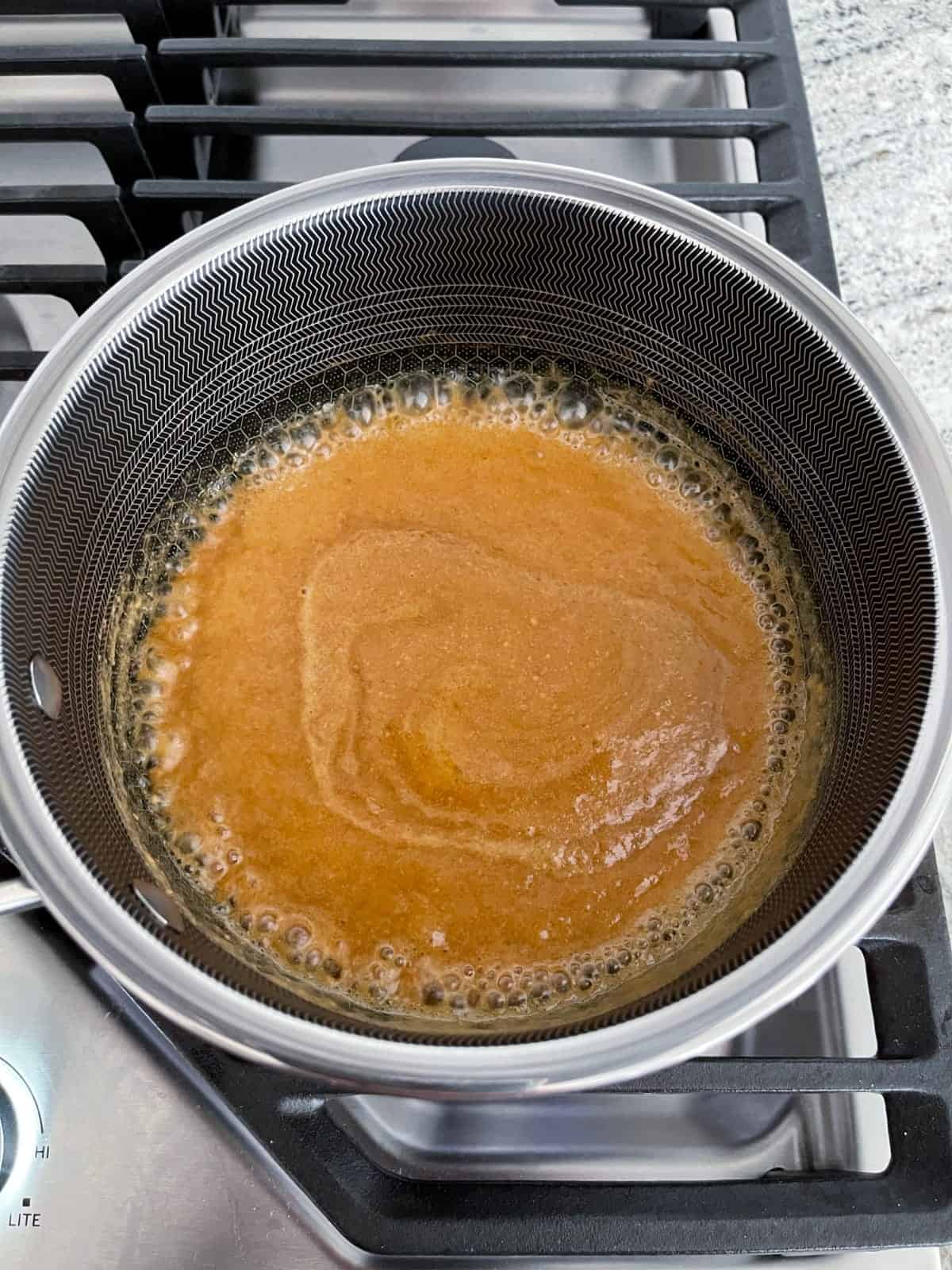 Boiling monk fruit sweetener, Truvia brown sugar, milk, butter and peanut butter in saucepan on stovetop.