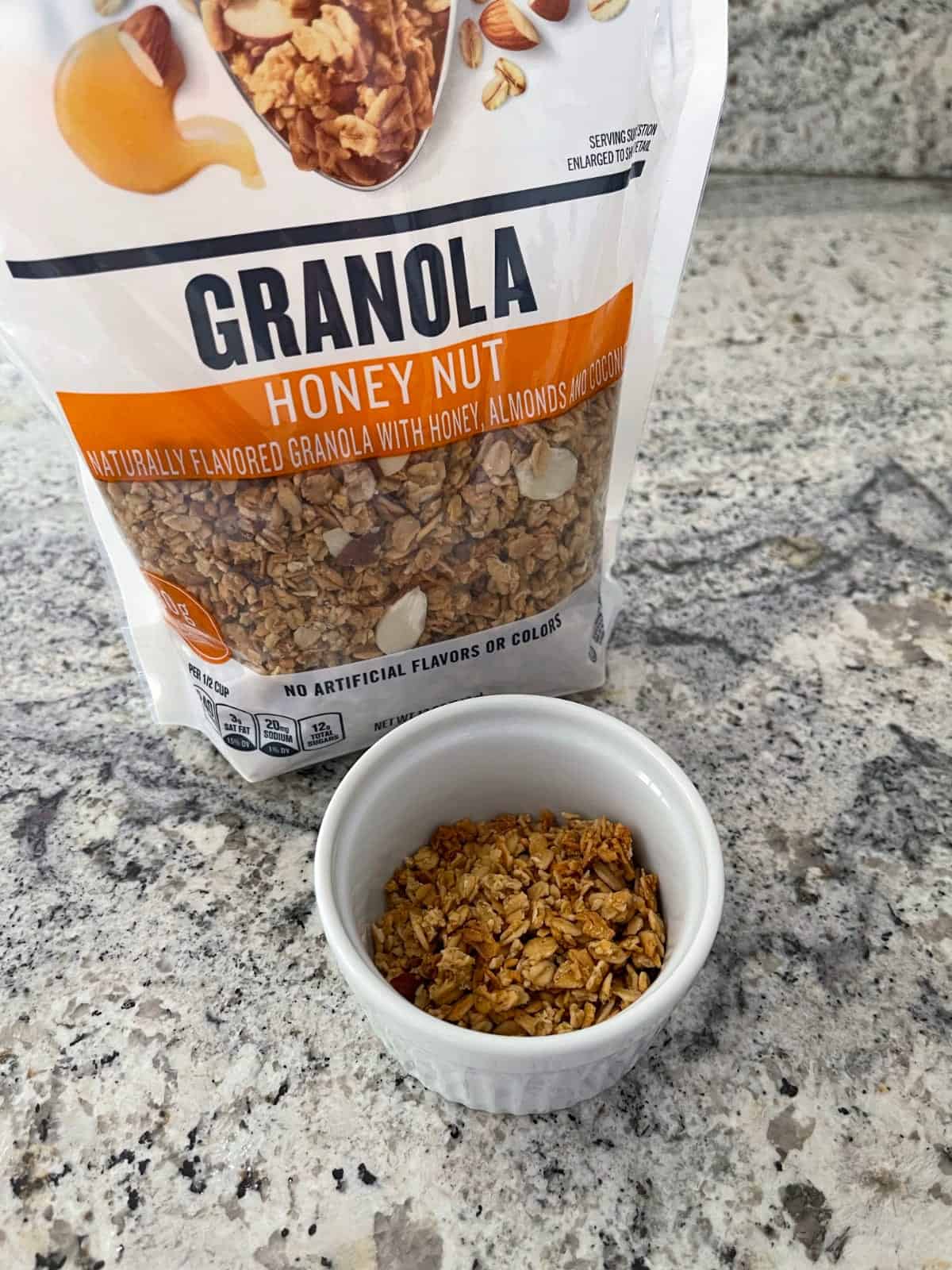 Package of honey nut granola with some in small white bowl.