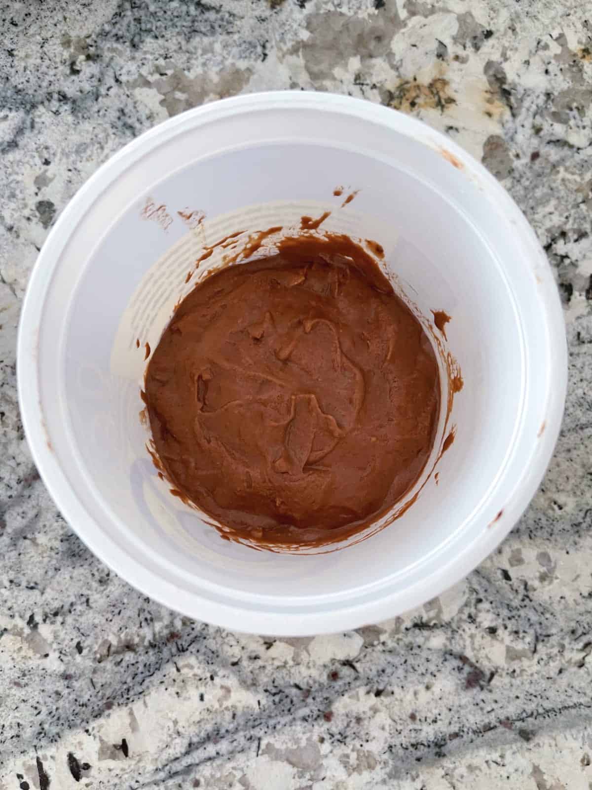 Unfrozen peanut butter chocolate nice cream in white container.