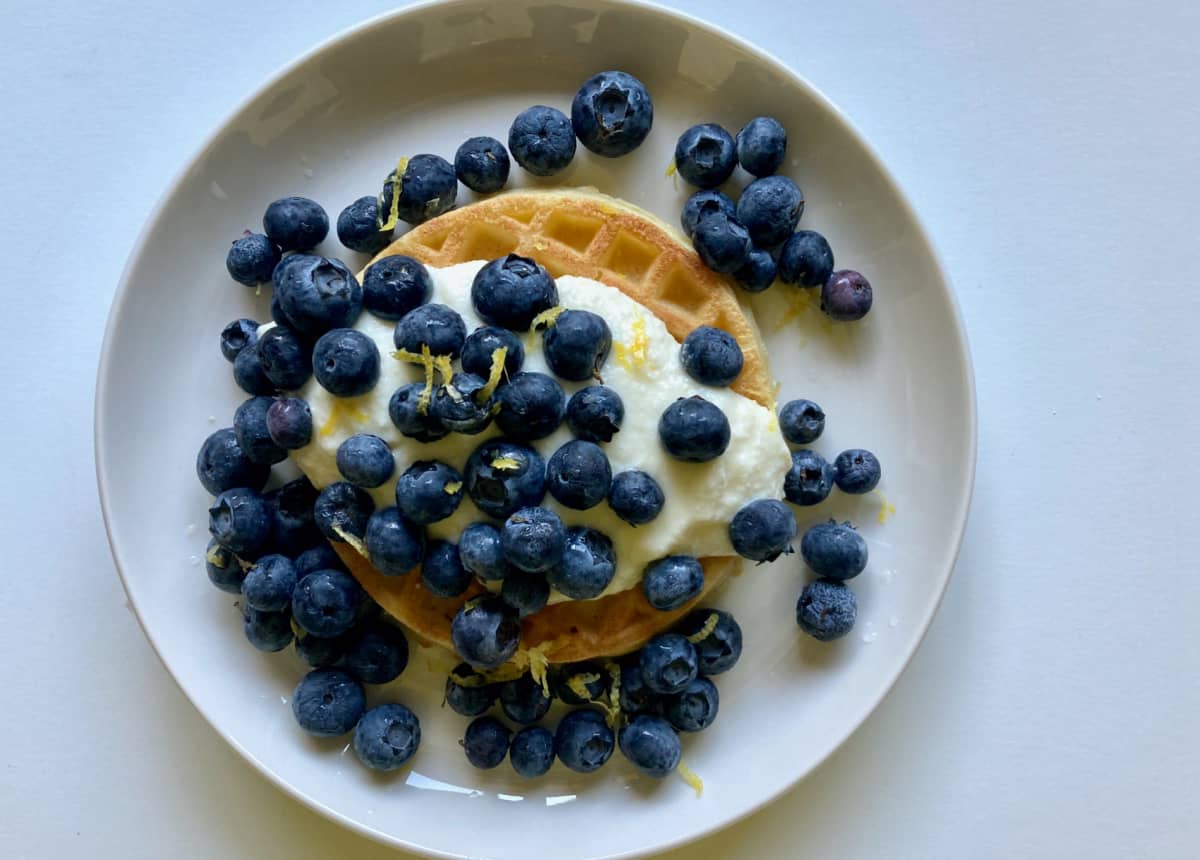 Whole grain waffle topped with lemon ricotta and fresh blueberries.