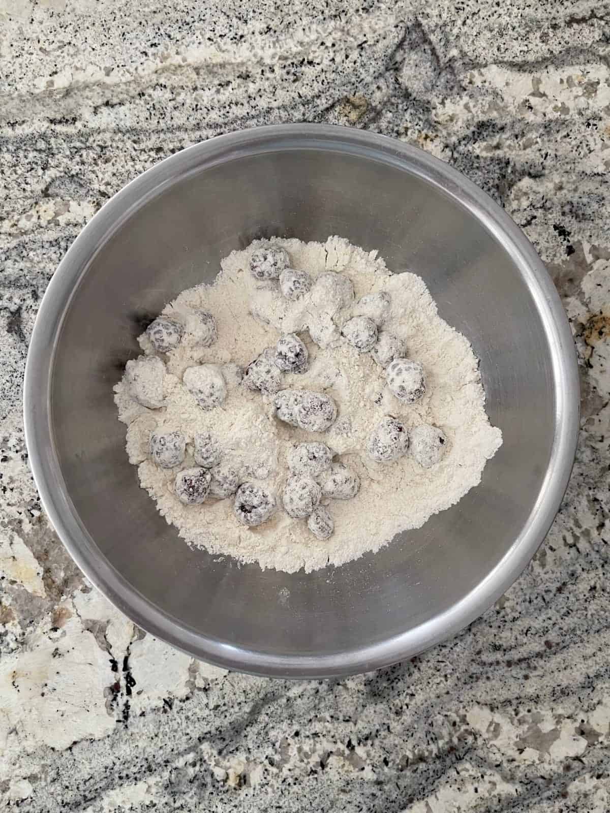 Blackberries coated in flour mixture in stainless mixing bowl.