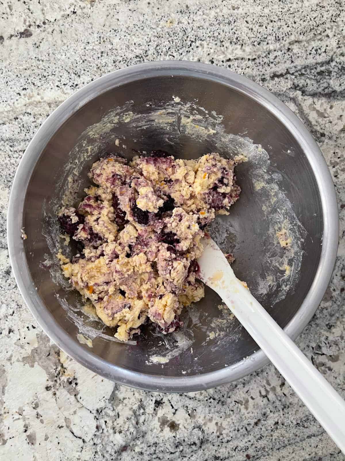 Mixing blackberry muffin batter in stainless bowl with spatula.