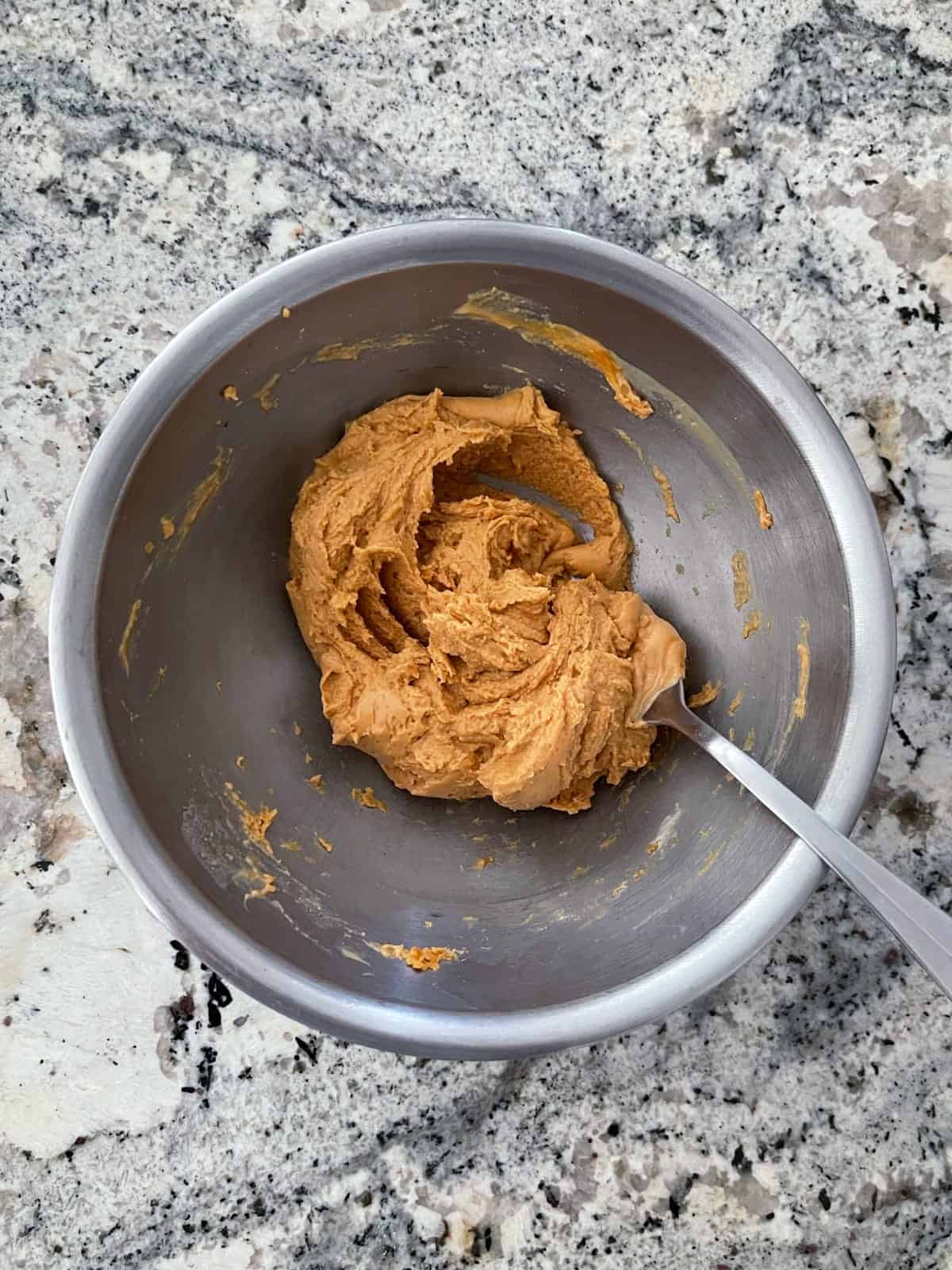 Combining peanut butter powder and water in mixing bowl with fork.