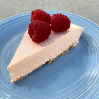 slice of no bake orange creamsicle pie topped with fresh raspberries on blue fiesta ware plate from above