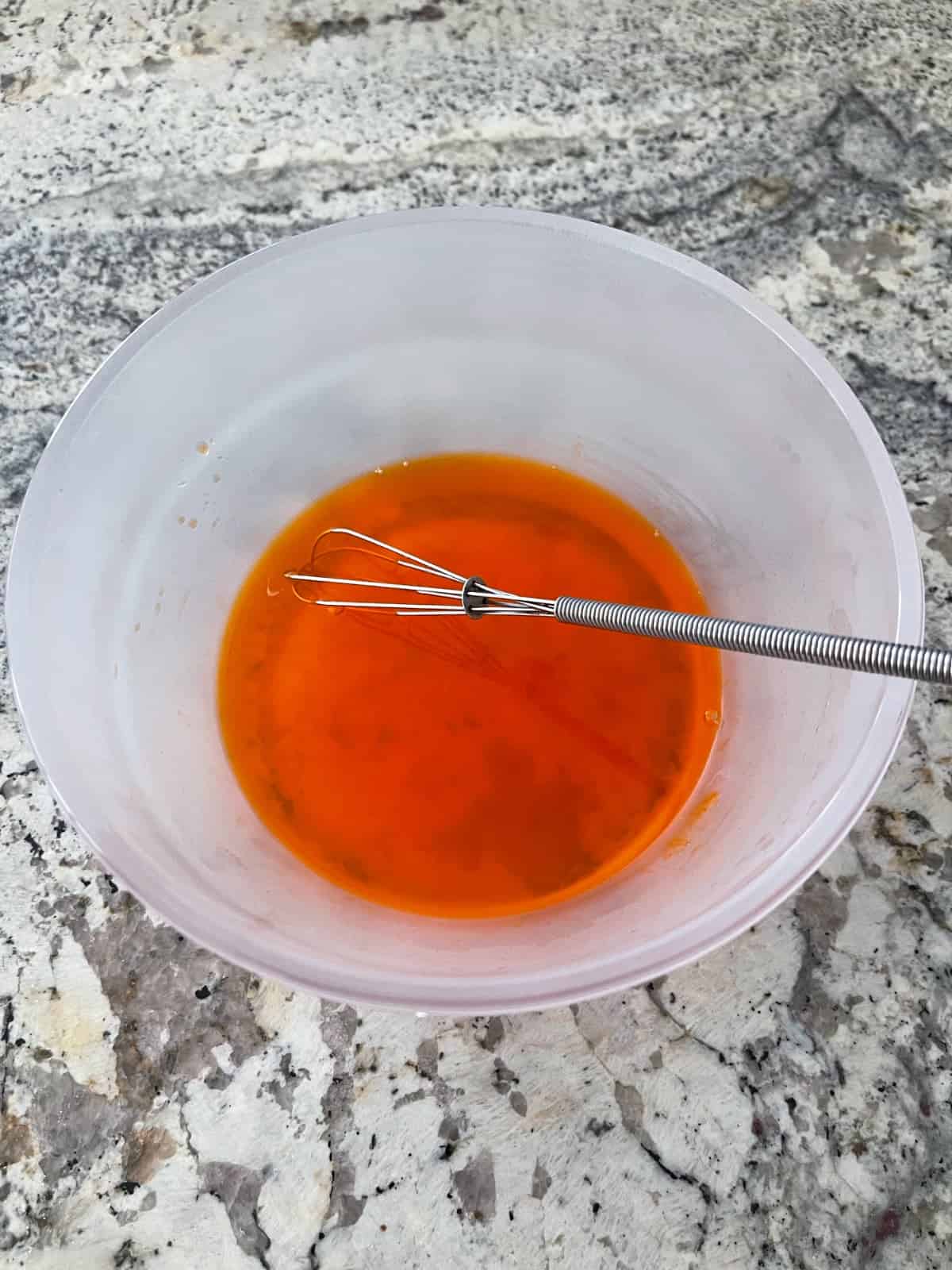 Whisking sugar-free orange Jello in glass bowl.