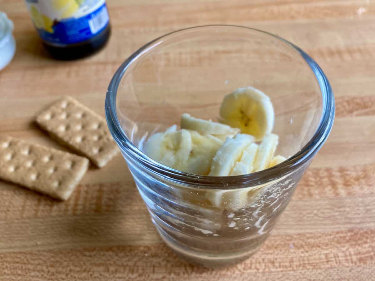 Dessert glass with crushed graham cracker and sliced banana.