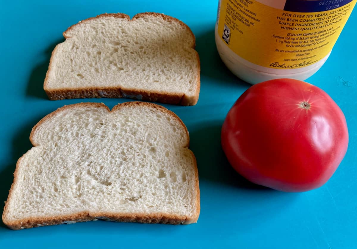 Two slices white bread, garden fresh tomato and jar of mayonnaise.