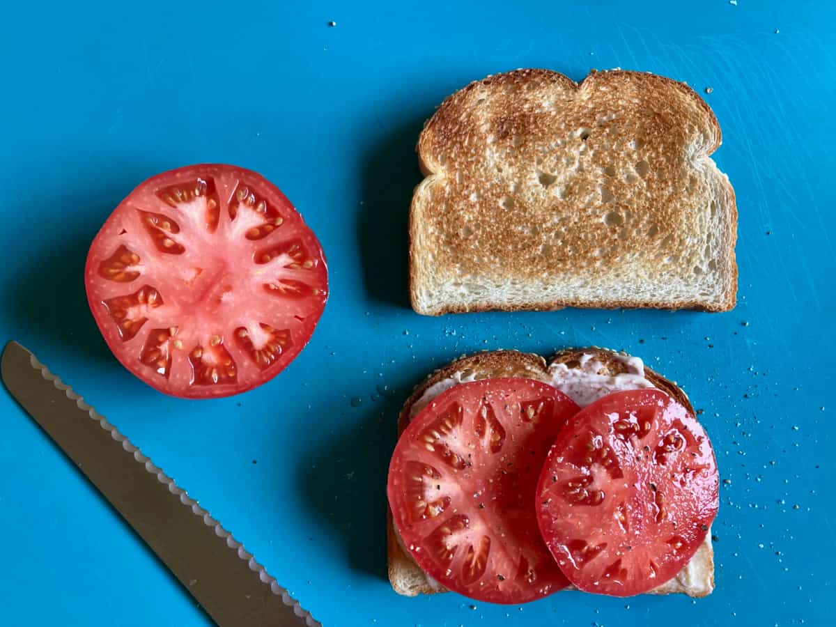 Toasted bread spread with mayonnaise and sliced tomatoes.