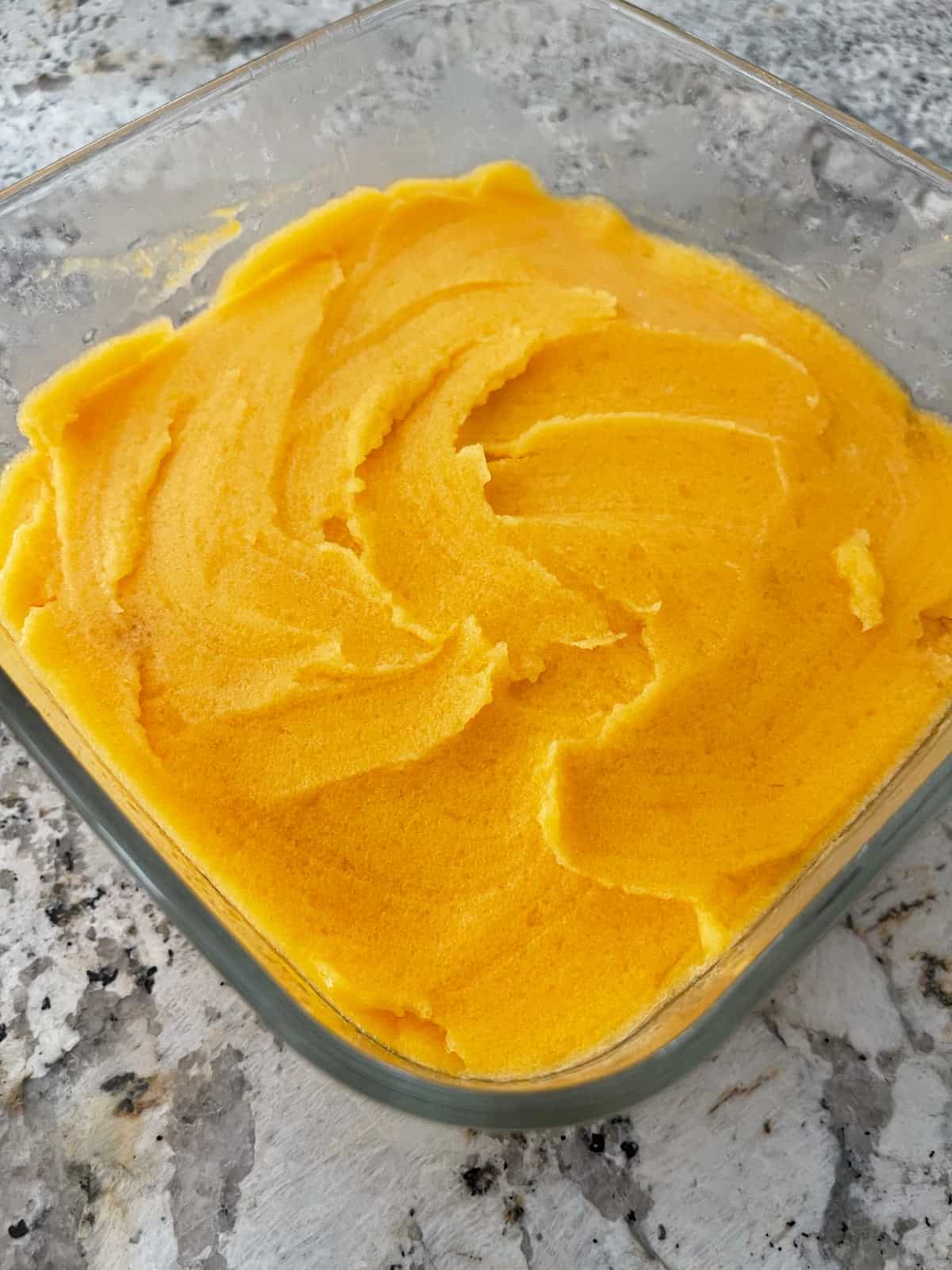 Creamy apricot sorbet in glass container.
