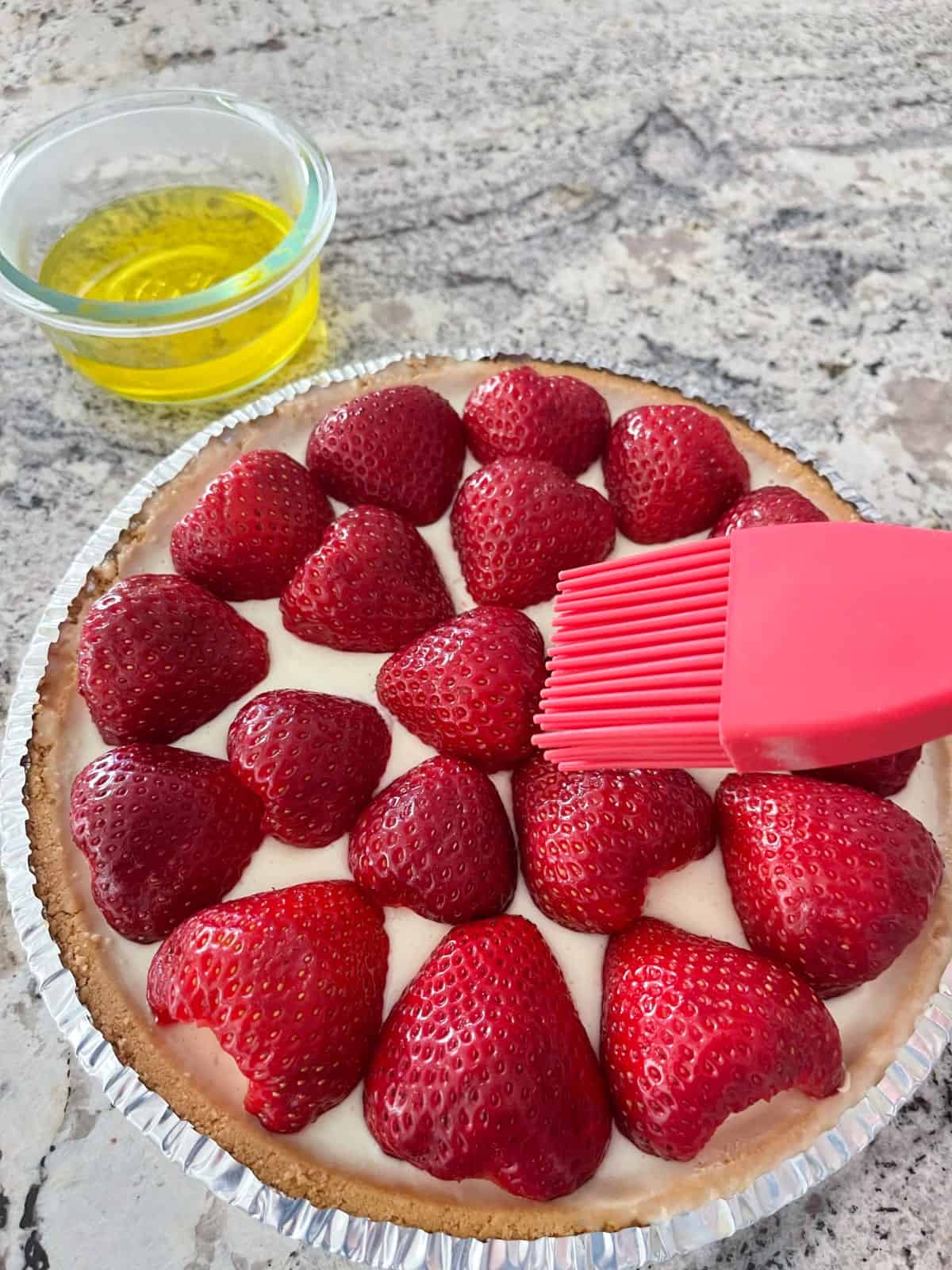Brushing lemon Jello over strawberries topped lemon yogurt pie.