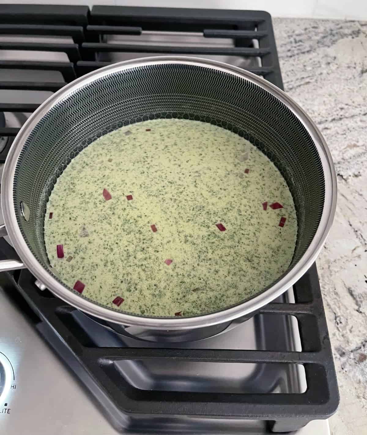 Cooking broccoli slaw risotto on saucepan on stovetop.