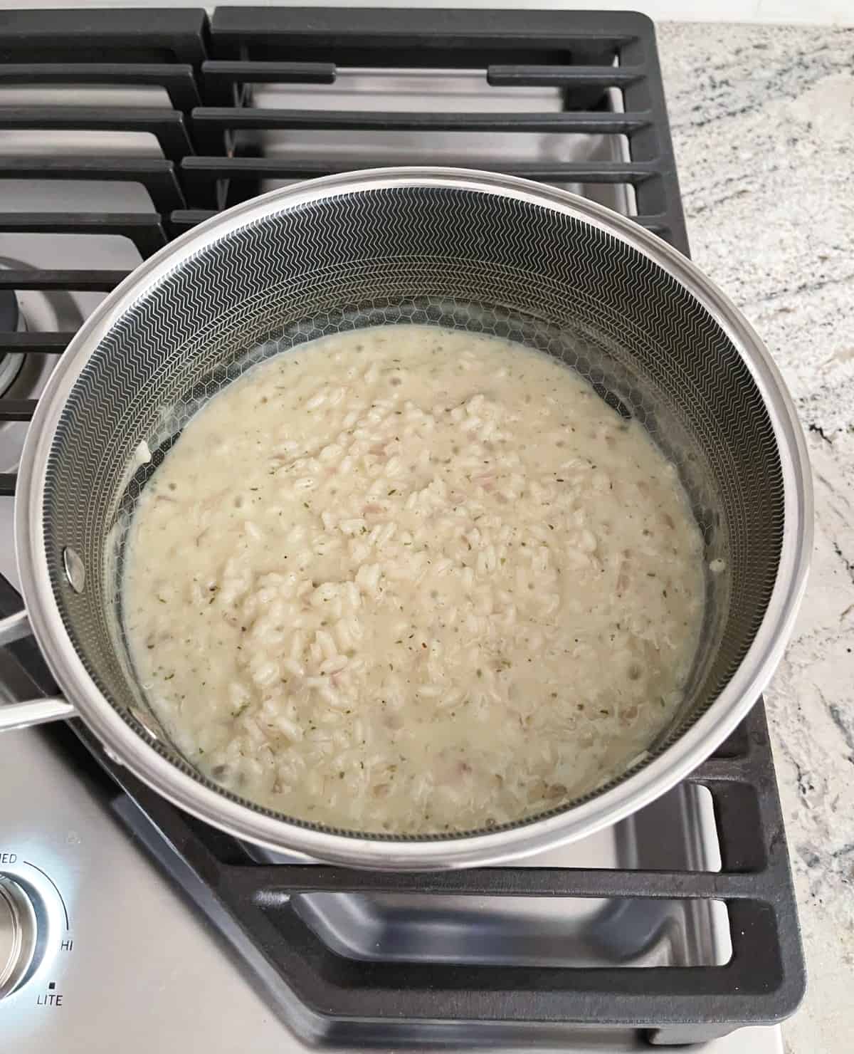 Cooking creamy parmesan risotto package mix in saucepan on stovetop.