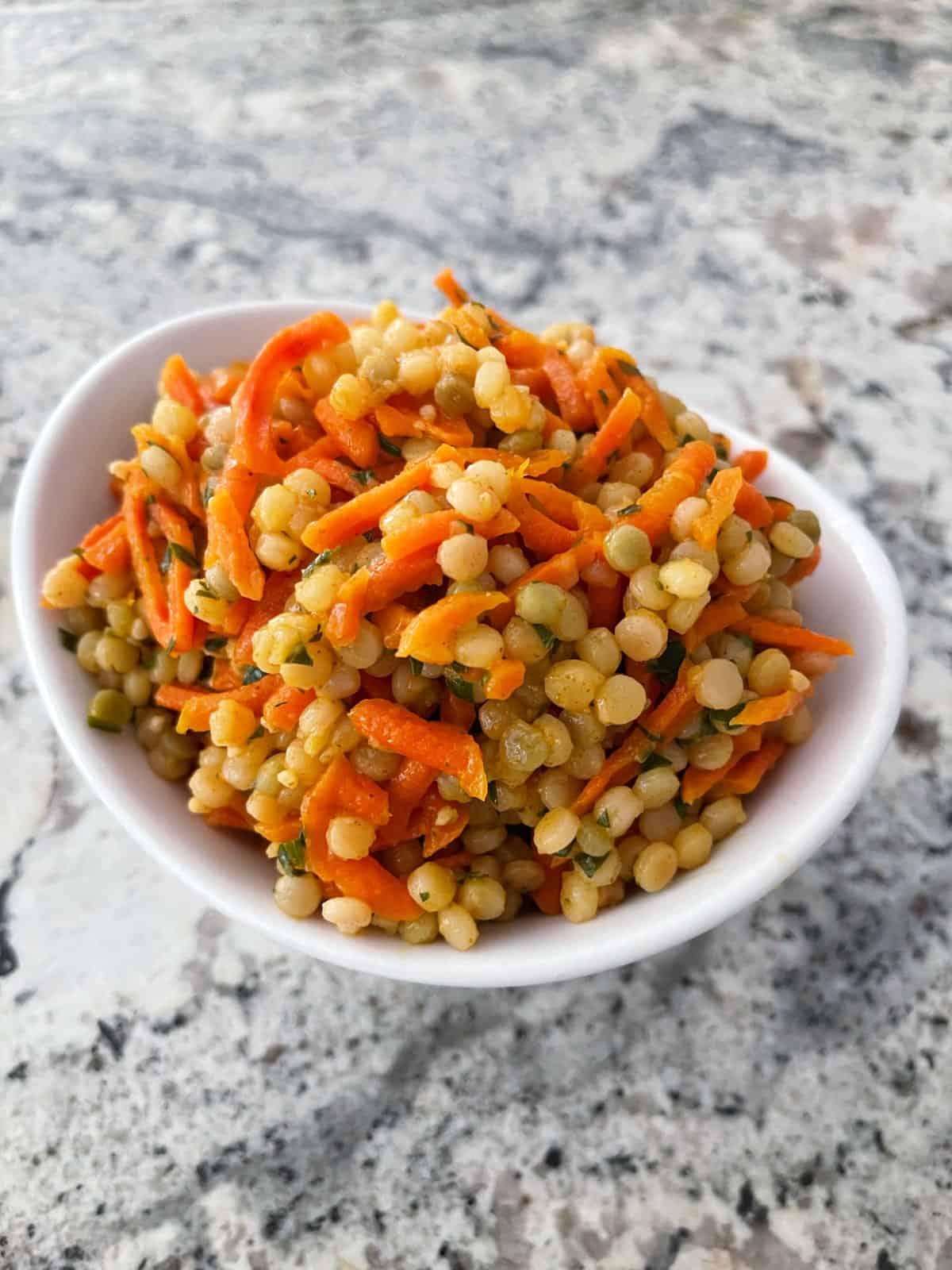 Simple carrot couscous salad in white bowl.