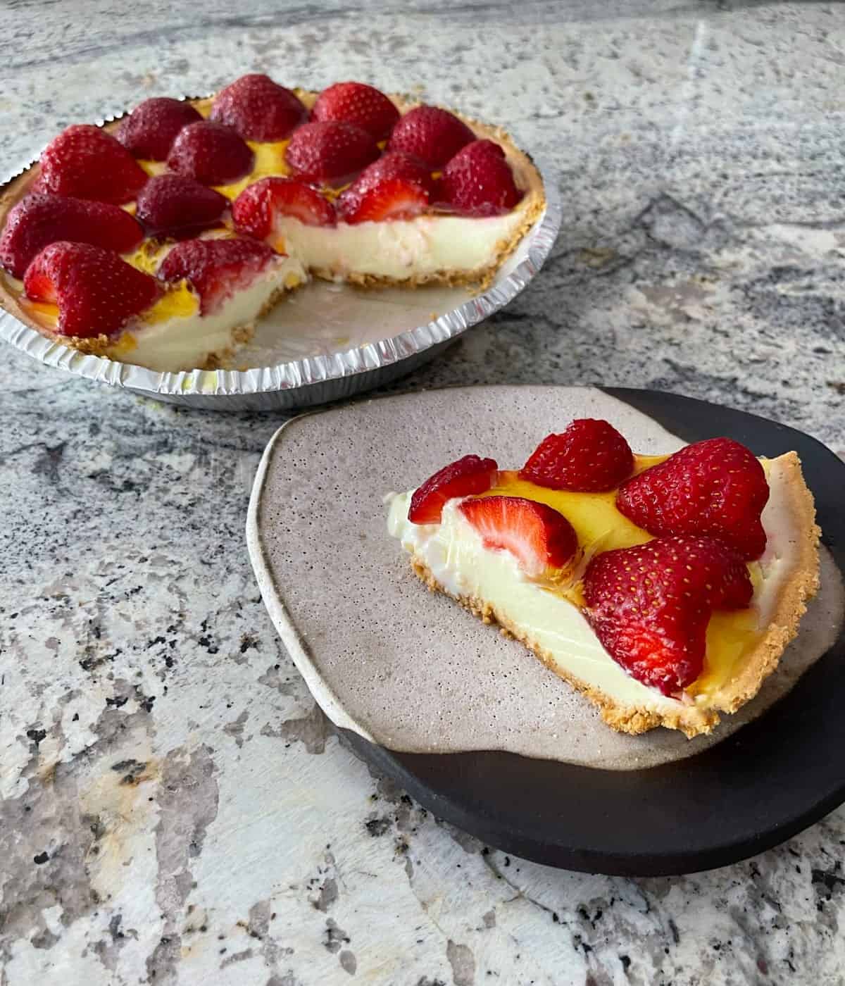 Slice of lemon strawberry pie with rest of pie in background.