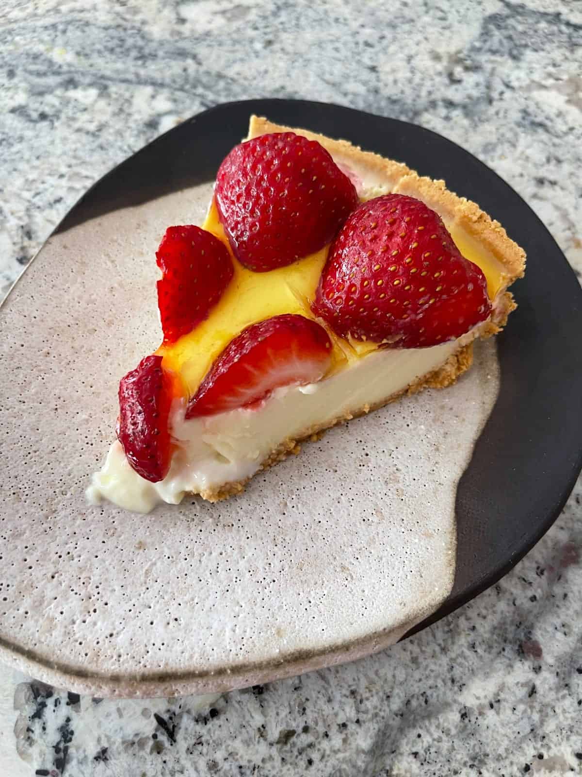 Slice of lemon strawberry no-bake pie on ceramic plate.