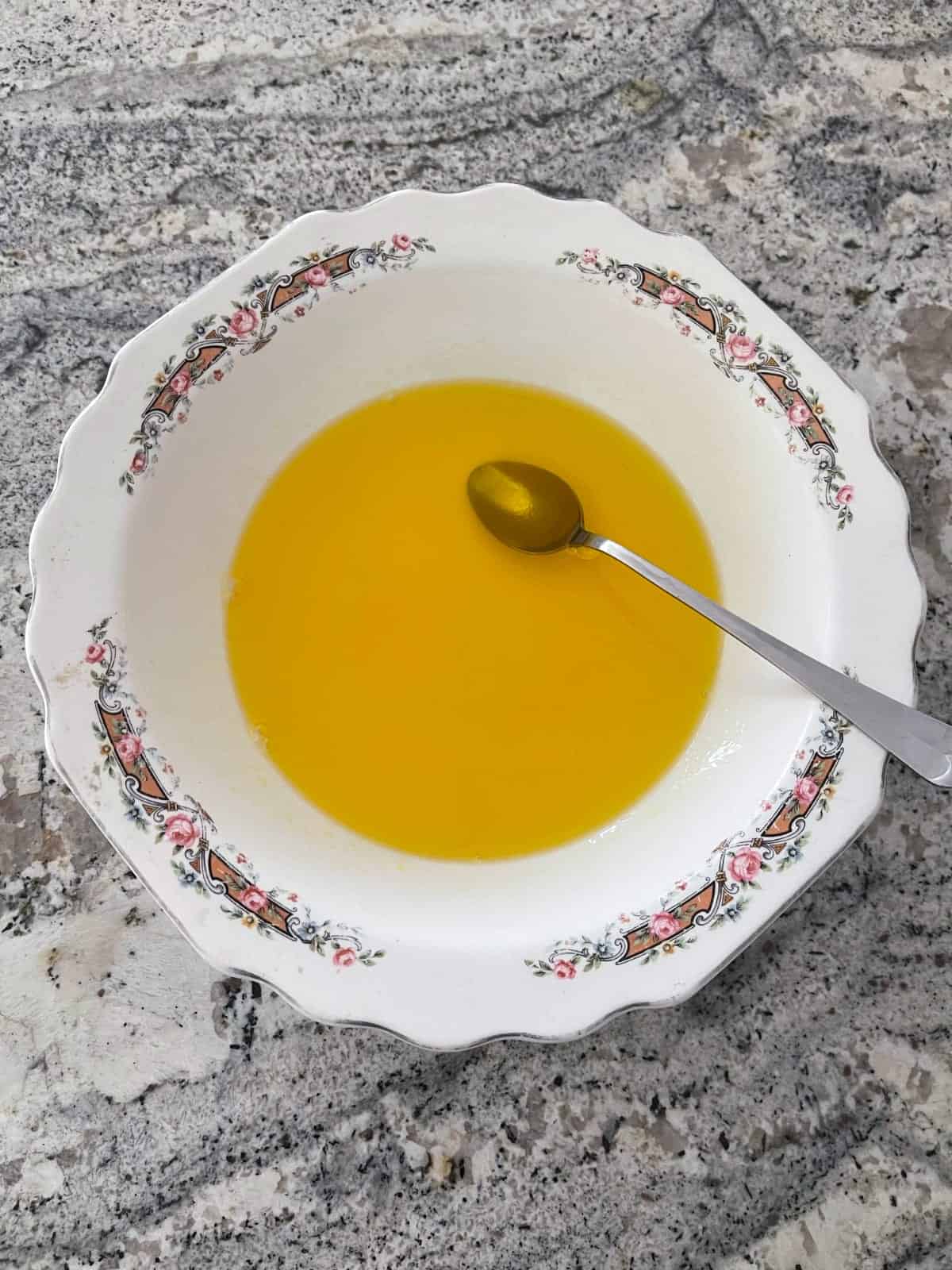 Dissolving lemon Jello in boiling water in white bowl.
